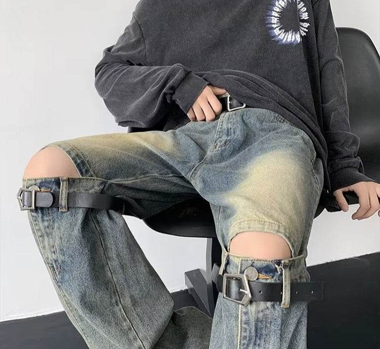 Model purtand Blugi prespălați retro cu detaliu din metal. Decupaje la genunchi si curele cu catarame pentru look streetwear