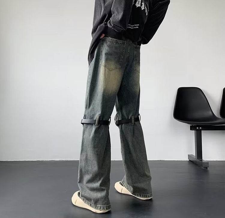 Model văzut din spate purtând Blugi prespălați retro cu detaliu din metal. Croială largă, buzunare și curele la genunchi.