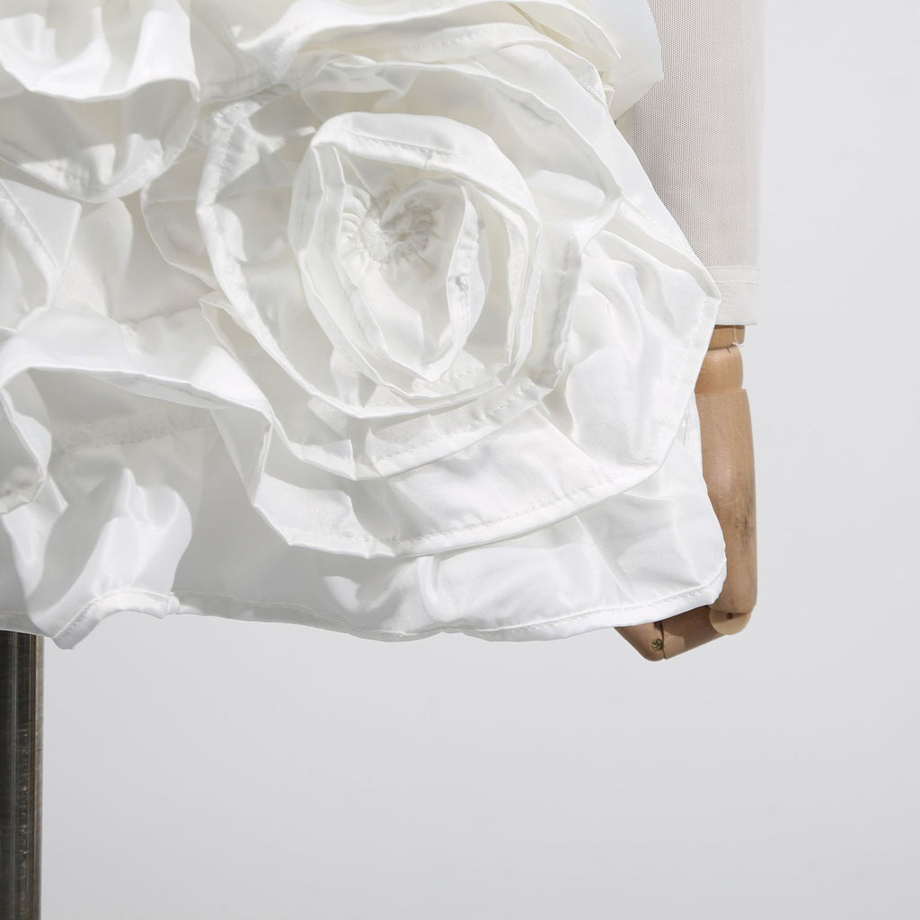 Close-up of a White Dress With 3D Flowers And Voluminous Skirt showcasing floral details and texture