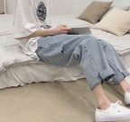 Casual model wearing wide jeans with folded hem and rips while reading on a sofa