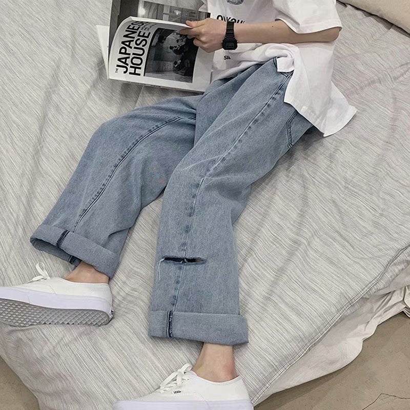 Casual outfit featuring Wide Jeans with Folded Hem and Rips paired with white sneakers on a bed