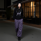 Woman wearing Wild Urban Leopard Cargo Pants paired with a black graphic sweatshirt in an urban setting