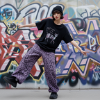 Model wearing Wild Urban Leopard Cargo Pants with a black graphic t-shirt against a colorful graffiti background