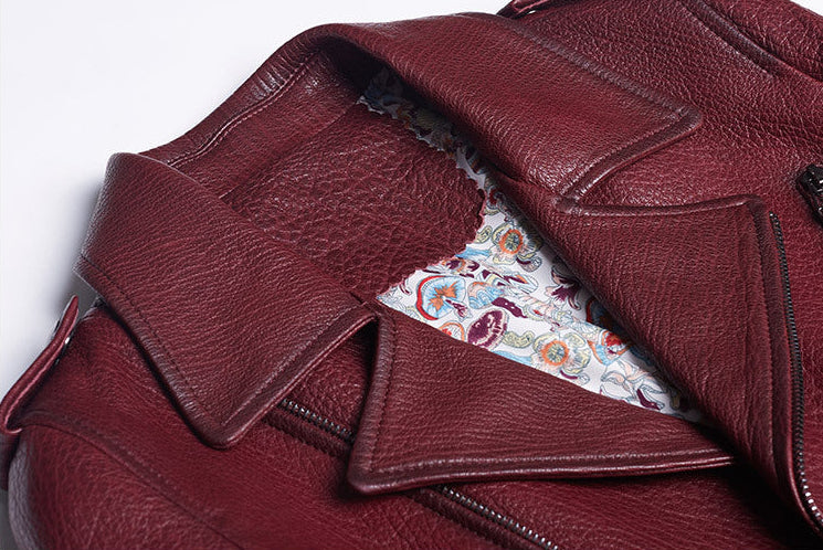 Close-up of women's wine leather moto jacket featuring intricate patterned lining for stylish allure
