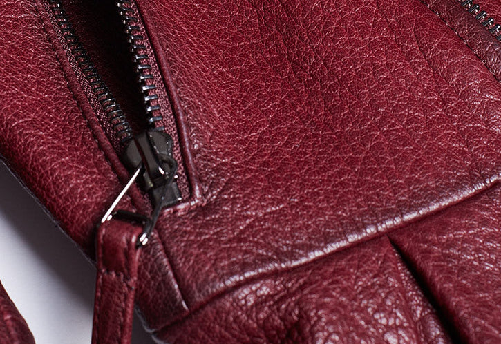 Close-up of women's wine leather moto jacket showcasing detailed zipper and texture